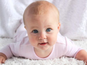 bébé allongé sur le ventre qui redresse la tête